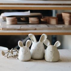 three ceramic rabbits sitting next to each other on a table