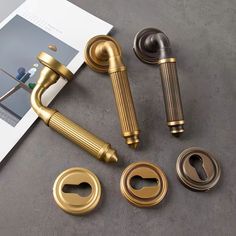 brass door handles and knobs are on the table next to an open magazine with photos