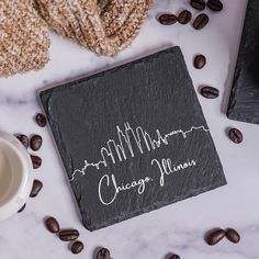 a black slate coaster with chicago skyline on it next to coffee beans