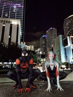 two spider - man cosplaying in the middle of a city at night