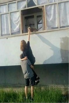 two young boys are reaching up to paint the outside of a house with words above them