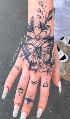 a woman's hand with tattoos on it and flowers in the middle of her left hand