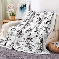 a white blanket with black and white images on it sitting in front of a couch