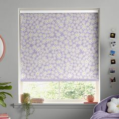 a bedroom with purple and white roman shades on the window sill, potted plant next to it