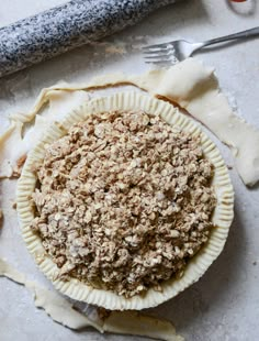 an uncooked pie sitting on top of a table next to a knife and fork