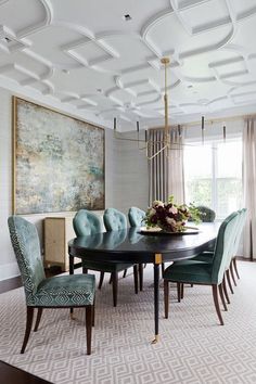 a dining room table with blue chairs and a large painting on the wall behind it