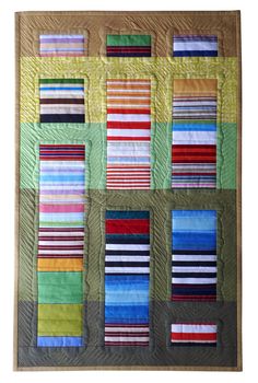 a quilted wall hanging with multiple strips of different colors on it's sides