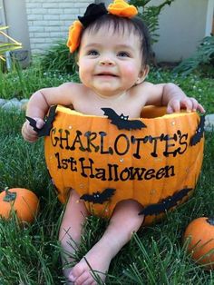 a baby in a pumpkin costume sitting on the grass with its head turned to look like it is holding a jack - o'- lantern