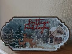 there is a christmas card on top of a shelf with a house and trees in the background