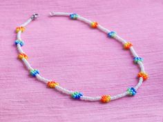 A dainty beaded necklace or bracelet with attractive and colorful rainbow daisy flowers. They are handmade with glass seed beads.   I also recommend to You: -✿-✿-✿-✿-✿-✿-✿-✿-  Check out all my daisies! ➤ DAISIES: https://www.etsy.com/shop/UnderRainbowDesign?search_query=daisy  You can find more of my rainbow jewelry here! ➤ RAINBOW: https://www.etsy.com/shop/UnderRainbowDesign?search_query=rainbow  My other floral jewelry could also be interesting! ➤ FLORAL JEWELRY: https://www.etsy.com/shop/Und White Flower Necklace With Colorful Beads For Summer, White Summer Flower Necklace With Colorful Beads, Summer White Flower Necklace With Colorful Beads, White Flower Necklace With Tiny Round Beads, White Flower Necklace With Tiny Beads, Dainty White Beaded Flower Necklace, Rainbow Daisy, Black Beaded Necklace, Rainbow Jewelry