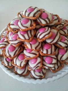 a white plate topped with lots of cookies covered in pink and white frosting on top of a table