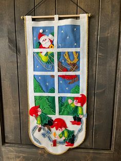 a christmas stocking hanging on a wooden door with santa and elves in the window