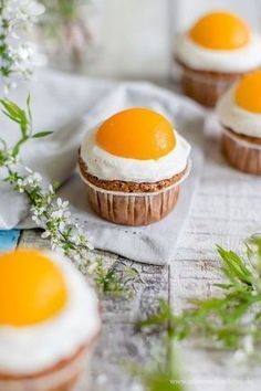 three cupcakes with an egg on top are sitting on a napkin next to some flowers