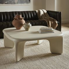 a white coffee table sitting on top of a carpeted floor next to a couch