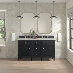 a bathroom with double sinks and mirrors on the wall, along with two hanging lights