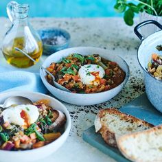 three bowls of food on a table next to bread