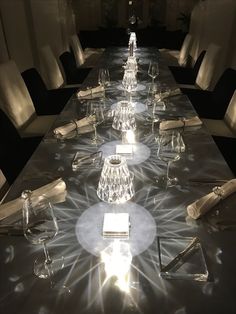 the long table is set with clear glasses and silverware