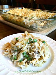 a white plate topped with pasta and peas next to a glass casserole dish