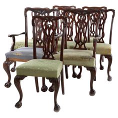 four carved wooden chairs with green upholstered cushions