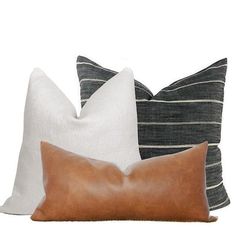 three pillows with different colors and patterns on them, one is brown, the other is white