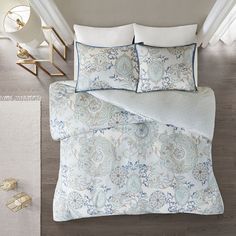 a bed with blue and white comforters on top of it next to a rug