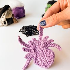 a hand holding a crocheted object in front of other knitted objects on a table