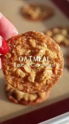 a hand holding an oatmeal cookie in front of other cookies