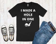 I Made A Hole In One Golf Shirt. Perfect as a golfing gift for both men and women. This classic unisex jersey short sleeve tee fits like a well-loved favorite. **Ladies - For unisex sizing: If you prefer a looser, casual fit order your normal size. If you prefer a slimmer fit, size down one** -Retail fit -100% Soft cotton - Heather colors are 52% Airlume combed and ring-spun cotton, 48% poly -Light fabric -Runs true to size Returns & Exchanges - I only accept returns & exchanges on cloth Black Golf T-shirt With Team Name, Black Cotton T-shirt For Golf, Crew Neck T-shirt With Team Name For Golf, Pre-shrunk Short Sleeve Tops For Golf, Cotton Graphic Tee For Golf, Graphic Cotton T-shirt For Golf, Cotton T-shirt With Letter Print For Golf, Funny Golf Shirts, Funny Golf