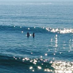 two surfers in the ocean on their surfboards with sun shining down over them