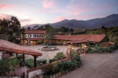 an aerial view of a house with a fountain in the front yard and mountains in the background