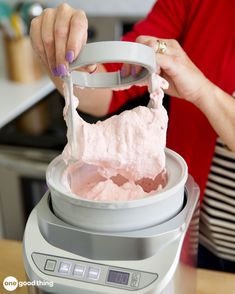 a woman is using a blender to make pink ice cream