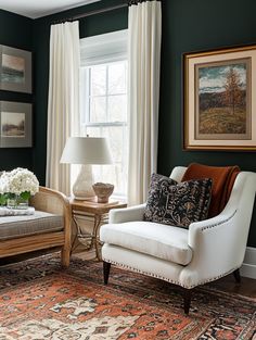 a living room with green walls and white curtains on the window sill, two chairs in front of a large area rug