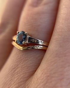 a woman's hand holding a ring with a blue stone on top of it