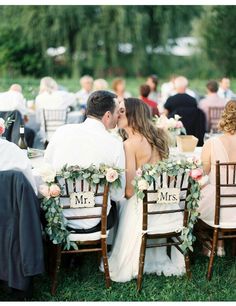 the bride and groom are kissing at their wedding reception in front of an outdoor crowd