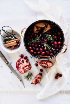 a pot filled with cranberries and spices next to a bowl of cinnamons