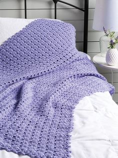 a purple crocheted blanket on top of a bed