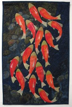 a quilted wall hanging with many orange fish on it