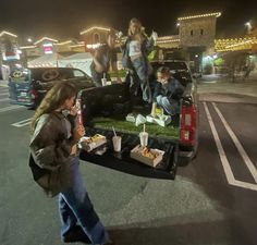 people are standing in the back of a truck with food on the bed and eating