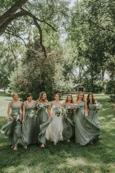 a group of bridesmaids posing for a photo in front of a large tree