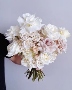 a person holding a bouquet of white and pink flowers