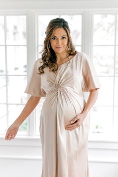 Our graceful Gwen Satin dress has been modified with a higher waistline and extra room to accommodate a growing bump, becoming the perfect option for the mommy-to-be in your bridal party! While a little more modest in coverage, the Gwen still features flutter sleeves and a delicate front twist detail that adds sophistication to a timeless design. FEATURES: Empire silhouette V-neckline Built-in bra cups and vertical boning for support Dolman flutter sleeves Back zipper Full-length double lining f Modest Maternity Dress With Short Sleeves, Feminine Short Sleeve Maternity Dress, Elegant Spring Maternity Dress Bump Friendly, Elegant Maternity Ruched Dress, Modest Maternity Midi Dress, Elegant Bump Friendly Spring Dresses, Elegant Maternity Dress With Ruched Detail, Elegant Spring Bump Friendly Dresses, Elegant Spring Dresses Bump Friendly