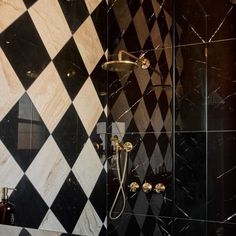 a black and white tiled bathroom with shower head, handset, and hand held showerhead