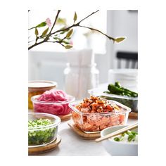 several bowls of food on a table with chopsticks and flowers in the background