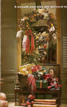 a christmas tree decorated with presents in front of a mirror and other holiday decorations on the wall