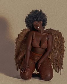 a woman with an angel wings on her body sitting in front of a beige background