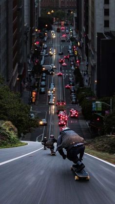 two skateboarders are riding down the street at night