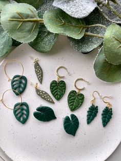 green leaf earrings on a plate next to some leaves