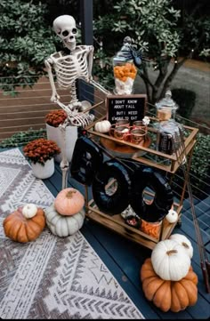 a skeleton sitting on top of a table next to pumpkins