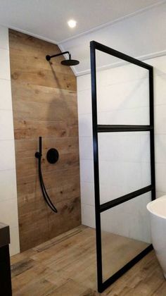 a modern bathroom with wooden floors and white walls, including a freestanding shower stall