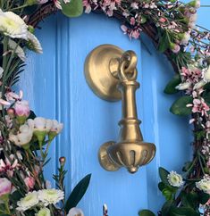 a blue door with a wreath on it and a gold key hanging from the handle